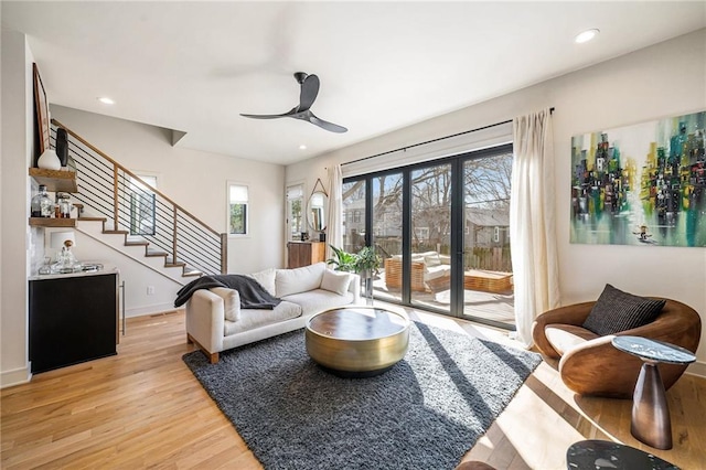 living room featuring light wood-type flooring, recessed lighting, baseboards, ceiling fan, and stairs