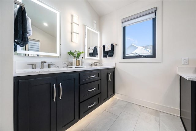 bathroom featuring a sink, baseboards, and double vanity