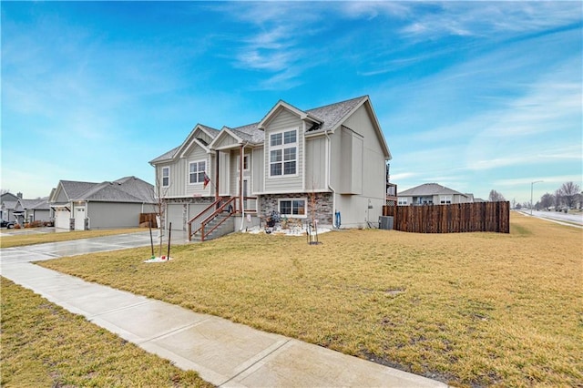 view of front of house with concrete driveway, central AC unit, a front yard, fence, and stone siding