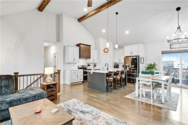 living room with high vaulted ceiling, beam ceiling, light wood-style flooring, and an inviting chandelier