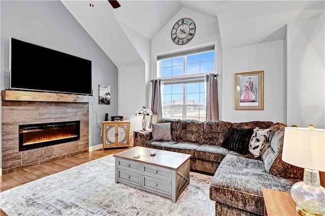 living room featuring lofted ceiling, a fireplace, and wood finished floors