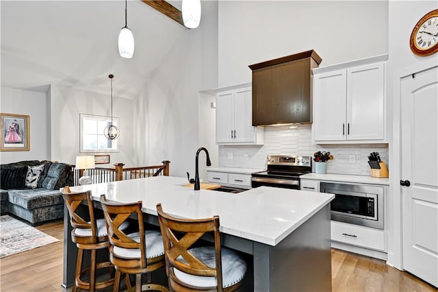 kitchen featuring light wood finished floors, a sink, stainless steel appliances, light countertops, and backsplash