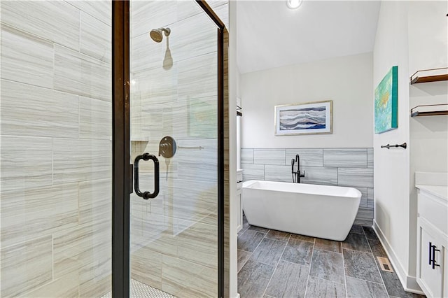 full bath featuring vanity, visible vents, a freestanding bath, tile walls, and a shower stall