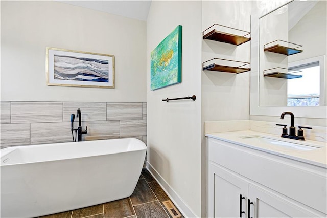 bathroom featuring a freestanding tub, vanity, and tile walls