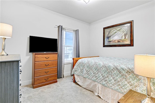 bedroom with light colored carpet and baseboards