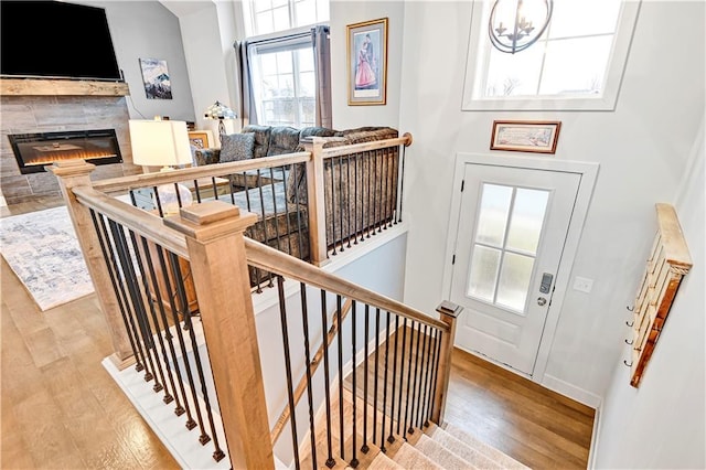 entryway with an inviting chandelier, wood finished floors, and a glass covered fireplace