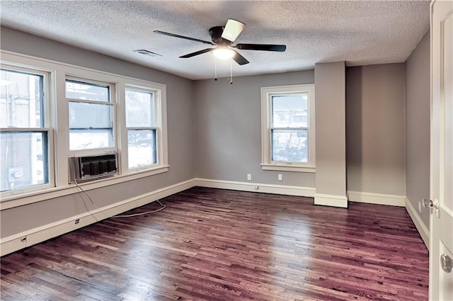 empty room with a healthy amount of sunlight, dark wood-type flooring, a textured ceiling, and ceiling fan