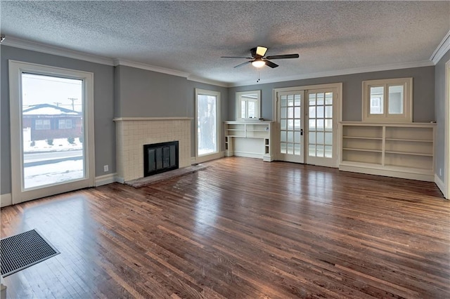 unfurnished living room featuring french doors, ornamental molding, dark hardwood / wood-style flooring, a healthy amount of sunlight, and a fireplace