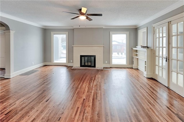 unfurnished living room with ornamental molding, a fireplace, light hardwood / wood-style flooring, and a textured ceiling