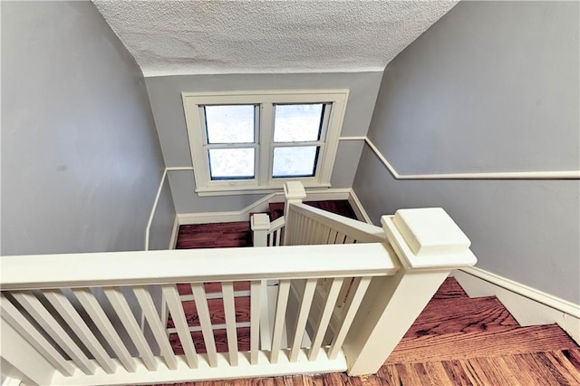 stairway with hardwood / wood-style floors and a textured ceiling