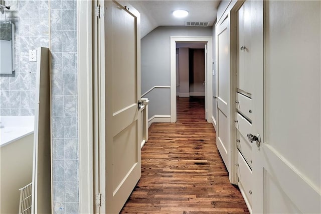 hallway with vaulted ceiling and dark hardwood / wood-style flooring