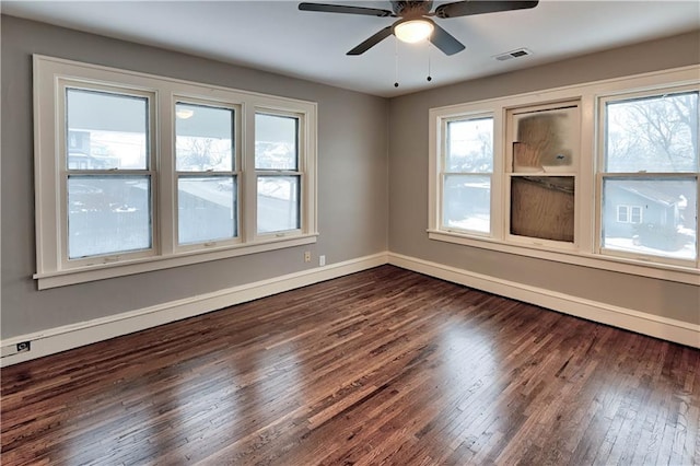 spare room featuring ceiling fan, a wealth of natural light, and dark hardwood / wood-style flooring