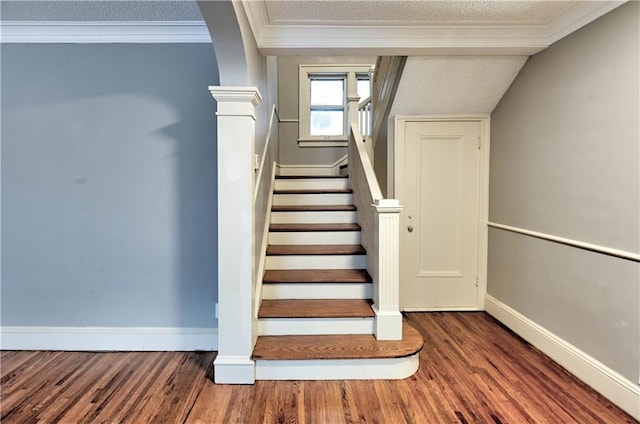 stairway featuring crown molding, wood-type flooring, and a textured ceiling