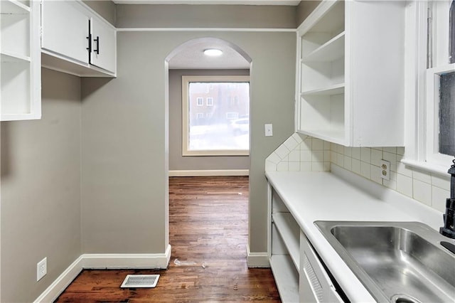 kitchen with tasteful backsplash, white cabinetry, sink, and dark hardwood / wood-style floors