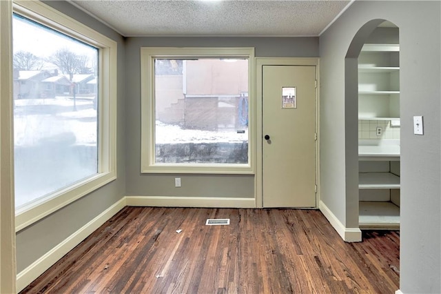 entryway with dark wood-type flooring and a textured ceiling