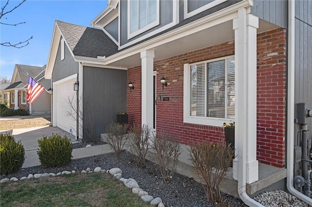 view of exterior entry with a shingled roof, brick siding, driveway, and an attached garage