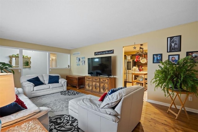 living area with visible vents, light wood-style flooring, and baseboards