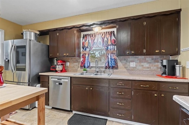 kitchen with dark brown cabinetry, appliances with stainless steel finishes, light countertops, and a sink