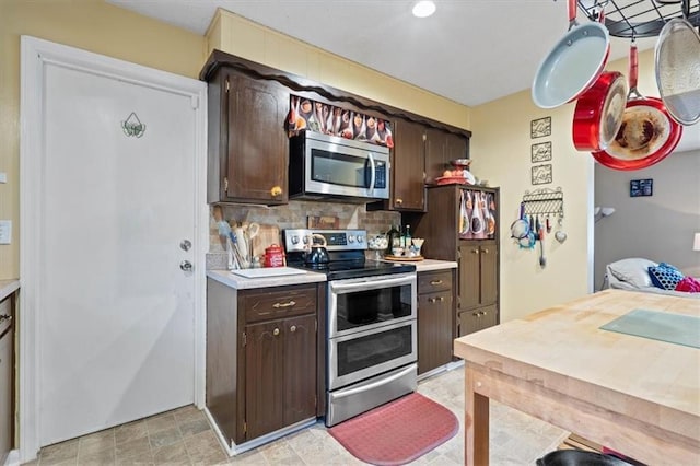 kitchen featuring stainless steel appliances, light countertops, dark brown cabinets, and tasteful backsplash