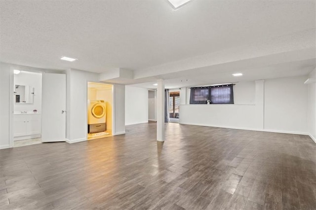 finished below grade area with a textured ceiling, washer / clothes dryer, dark wood-style flooring, and baseboards