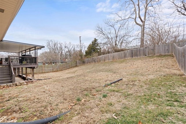 view of yard with a deck, a fenced backyard, and stairway