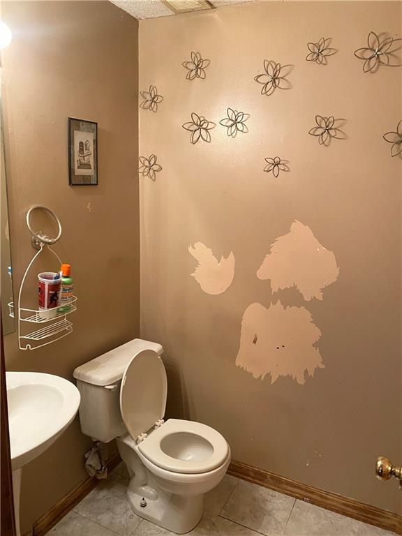 bathroom with toilet, tile patterned flooring, baseboards, and a sink