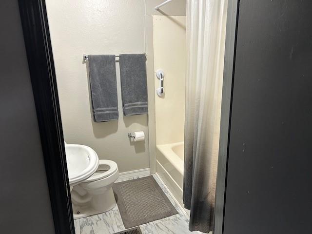 bathroom with shower / bath combination with curtain and toilet