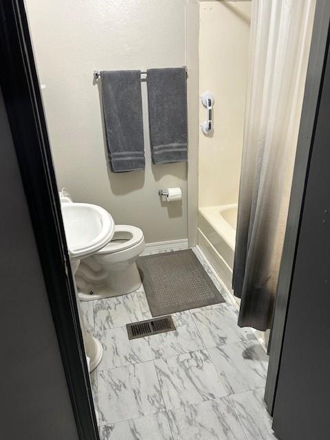 full bathroom with sink, shower / bathtub combination with curtain, and toilet