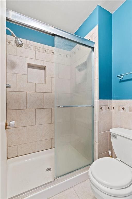 full bathroom with toilet, a shower stall, tile walls, and tile patterned flooring