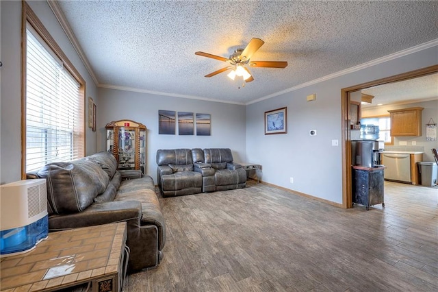 living area featuring light wood finished floors, plenty of natural light, ornamental molding, and a ceiling fan