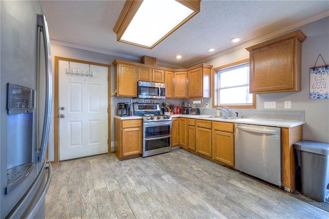 kitchen with light countertops, appliances with stainless steel finishes, a sink, and light wood-style flooring