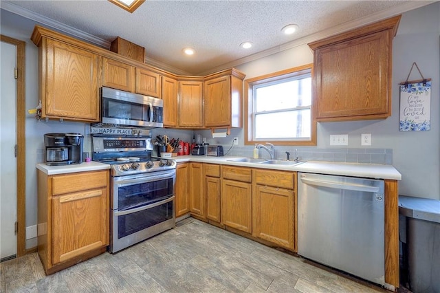 kitchen featuring stainless steel appliances, brown cabinetry, a sink, and light countertops