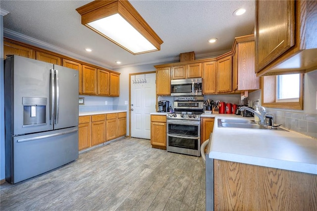 kitchen featuring light wood-style flooring, stainless steel appliances, a sink, and light countertops