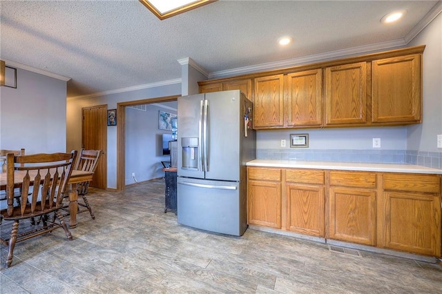 kitchen featuring a textured ceiling, light countertops, brown cabinets, and stainless steel fridge with ice dispenser