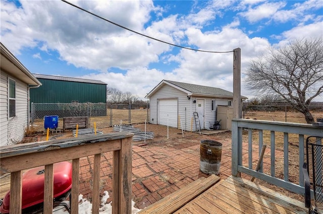 deck with an outbuilding, fence, a detached garage, and a patio