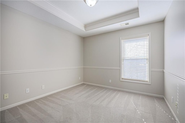 carpeted empty room with ornamental molding and a tray ceiling