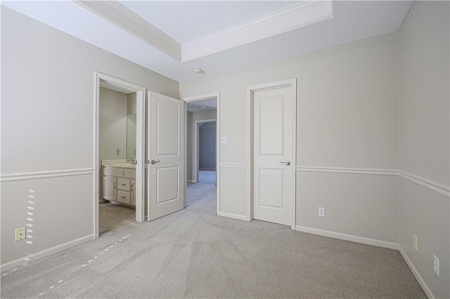 unfurnished bedroom with connected bathroom, sink, light colored carpet, a raised ceiling, and crown molding