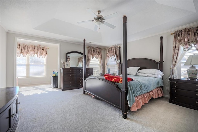 bedroom with a raised ceiling, crown molding, light carpet, and ceiling fan