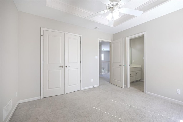 unfurnished bedroom featuring a closet, light colored carpet, ceiling fan, and a tray ceiling