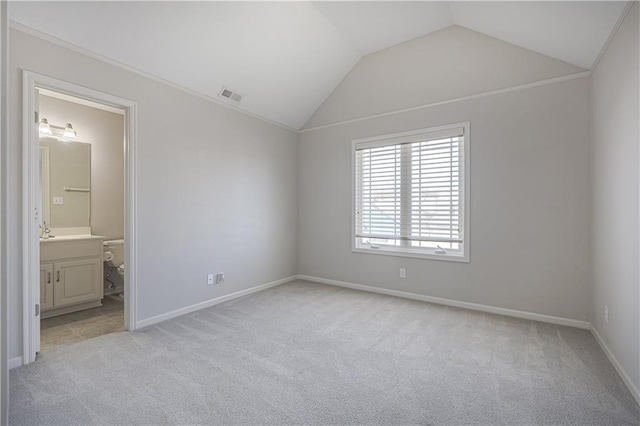 unfurnished bedroom with vaulted ceiling, connected bathroom, light colored carpet, and crown molding