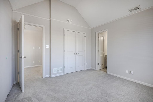 unfurnished bedroom with light colored carpet, vaulted ceiling, and a closet