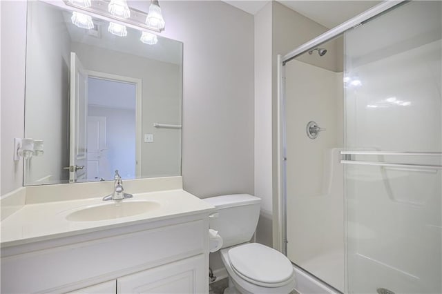 bathroom featuring vanity, a shower with door, and toilet