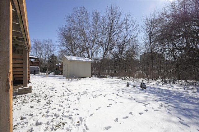 snowy yard featuring a shed