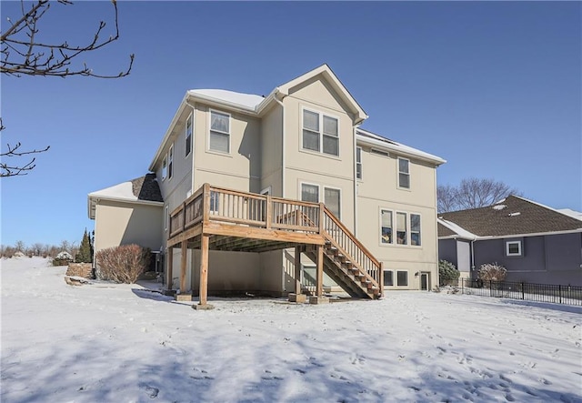 snow covered back of property with a deck