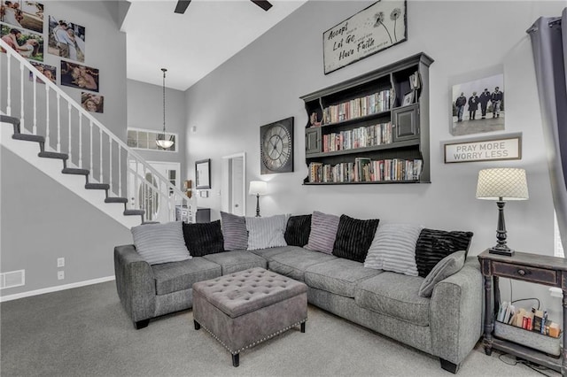 living room with carpet floors, stairs, a towering ceiling, baseboards, and ceiling fan with notable chandelier