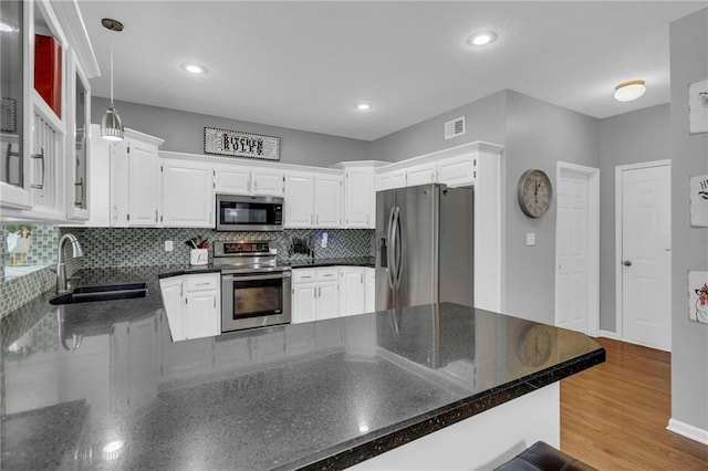 kitchen featuring a peninsula, a sink, visible vents, appliances with stainless steel finishes, and light wood finished floors