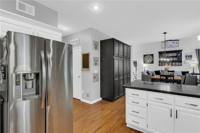 kitchen with light wood finished floors, dark countertops, visible vents, open floor plan, and stainless steel fridge with ice dispenser