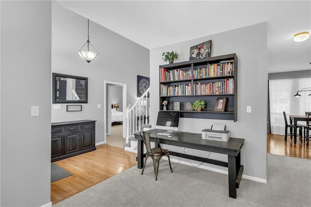 office featuring light carpet, light wood-style flooring, and baseboards