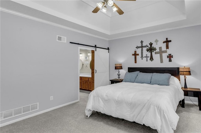 bedroom featuring light carpet, a tray ceiling, a barn door, and visible vents