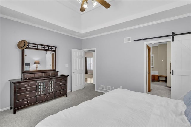 carpeted bedroom with a barn door, visible vents, and ornamental molding